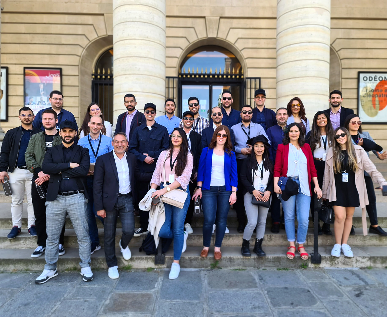 Photographie de groupe en couleur, qui montre 26 salariés de l’entreprise TECOS alignés, devant le théâtre de l’Odéon à Paris